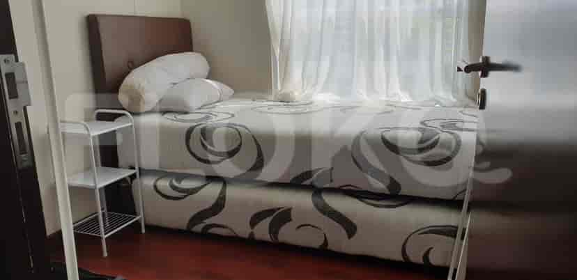 A bedroom with a double bed, side table and window.