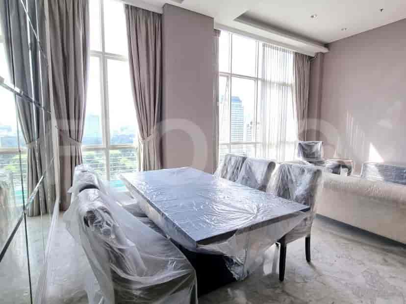 Dining area with a large table and chairs, all covered in plastic.