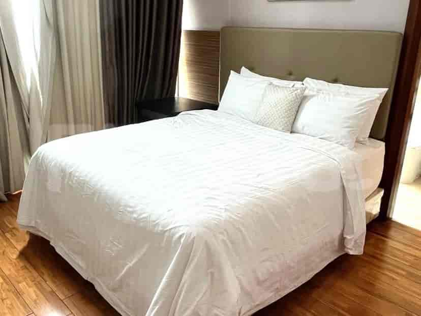Bedroom with a queen-sized bed, white bedding, and wooden flooring.