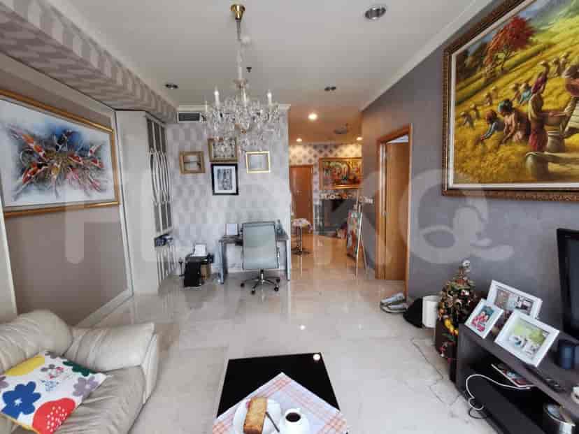 A living room with white sofa, chandelier, and various art pieces.