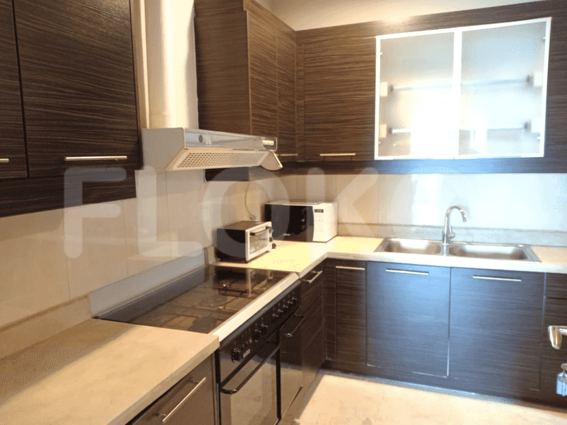 A modern kitchen with dark wood cabinets, stainless steel appliances, and a light countertop.