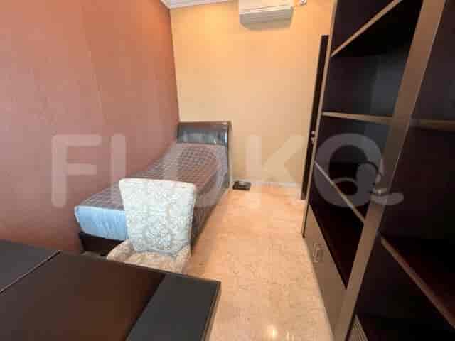 Kamar tidur kecil dengan tempat tidur single dan meja.