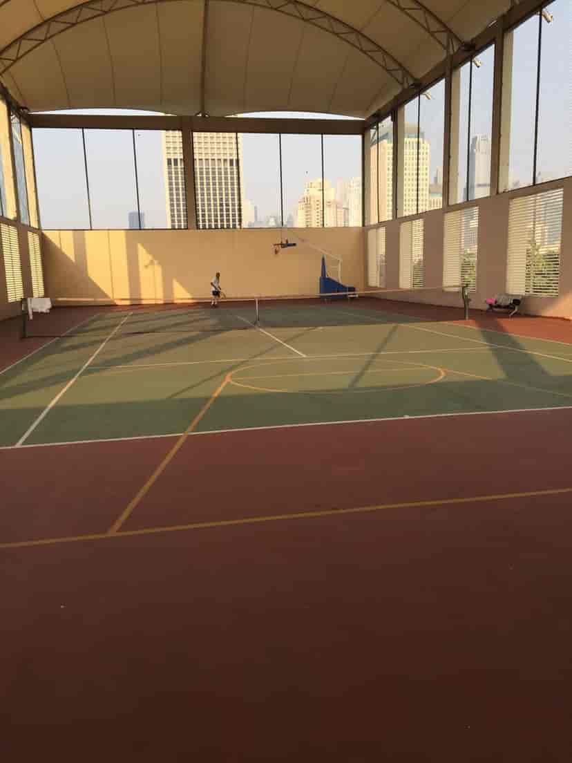 Lapangan tenis luar ruangan dengan jaring dan pagar di sekitarnya.