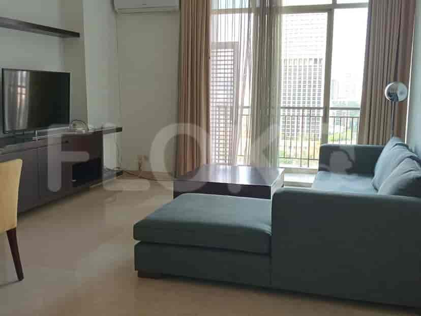 A modern living room with an L-shaped grey sofa, a large TV, and a balcony.