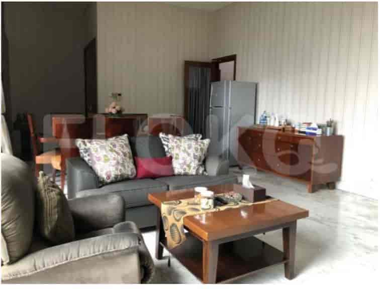 Ruang tamu dengan sofa abu-abu, meja kopi, dan bufet.