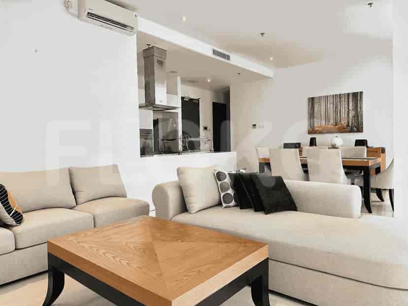 A well-lit living room with an L-shaped sofa, a coffee table, and a dining area.