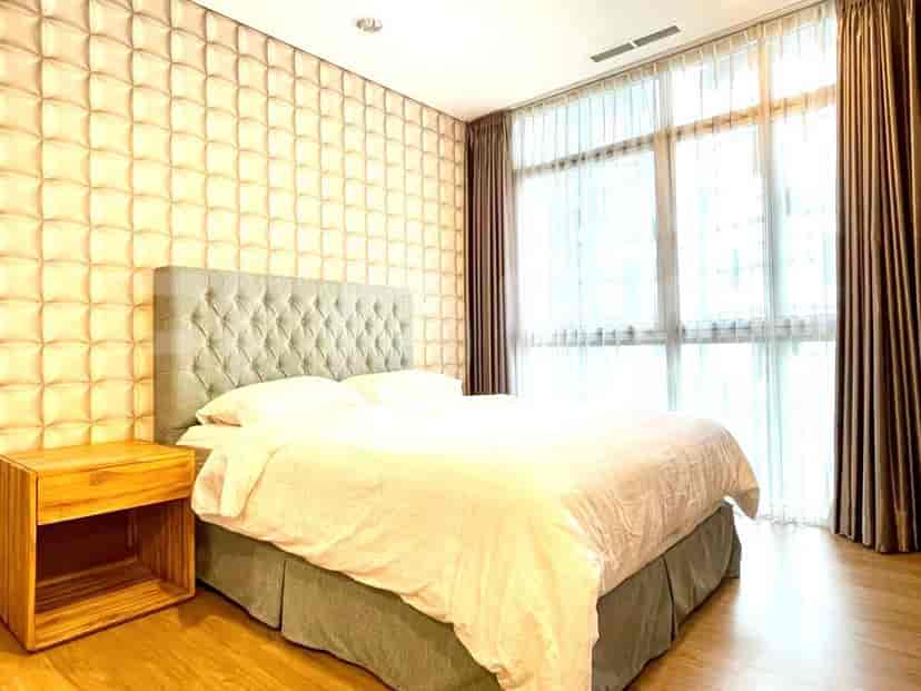 A modern bedroom with a tufted headboard and large windows.