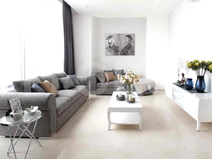 A bright, modern living room featuring a grey L-shaped sofa, side table, and white coffee table.