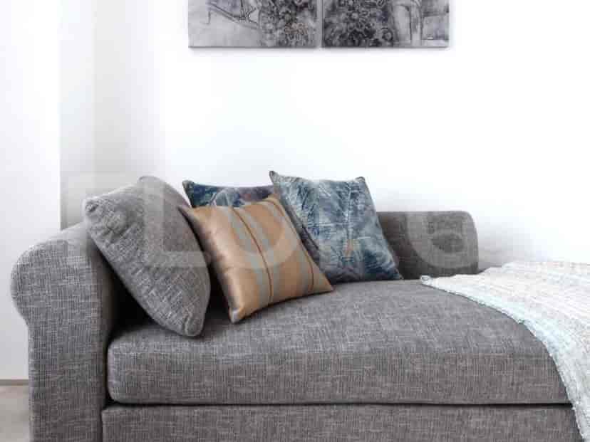 Close-up of a grey sofa with decorative cushions and a throw blanket.