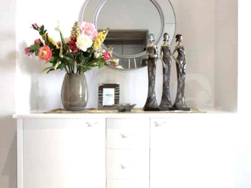 White cabinet with decorative mirrors and statues.