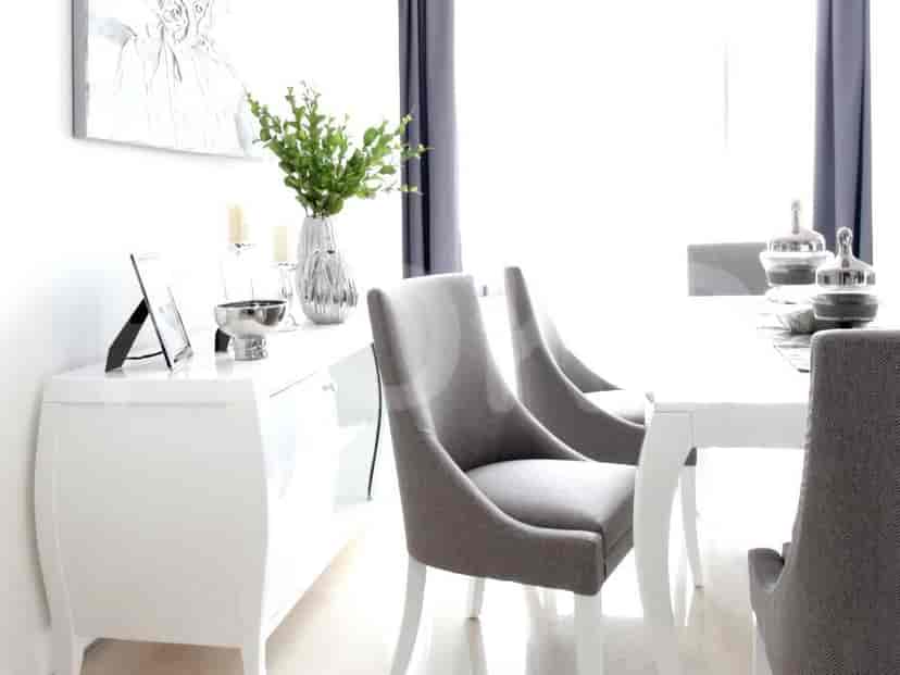 Dining area with white table and chairs, framed by white walls and curtains.