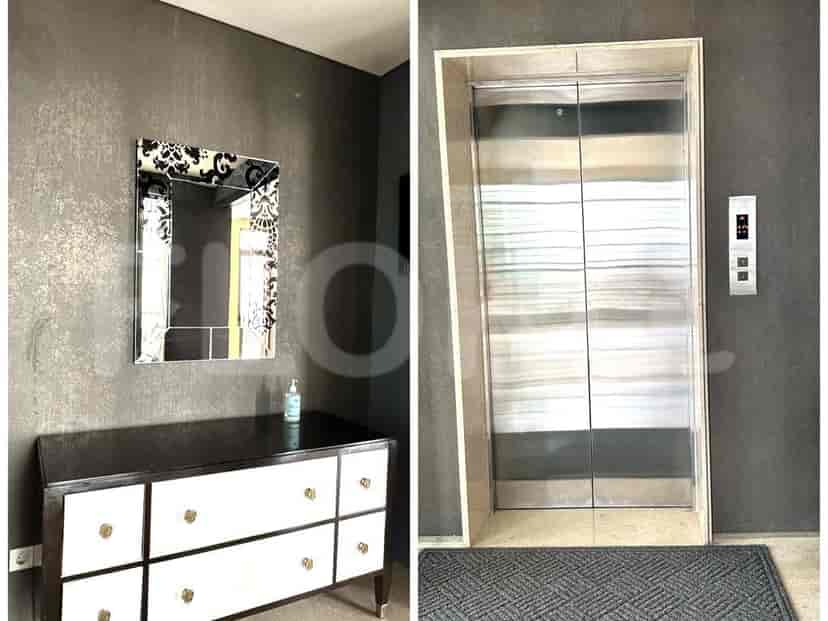 A modern entryway with a console table, decorative mirror, and elevator.