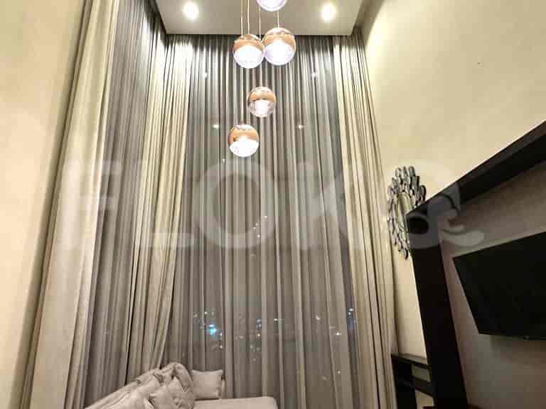 A bright living area with tall sheer curtains and hanging pendant lights.