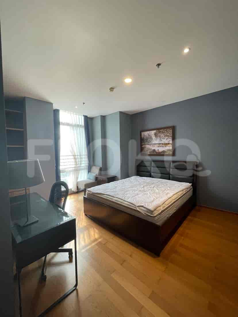 Bedroom with a dark-toned bed, wooden flooring, and a study desk.