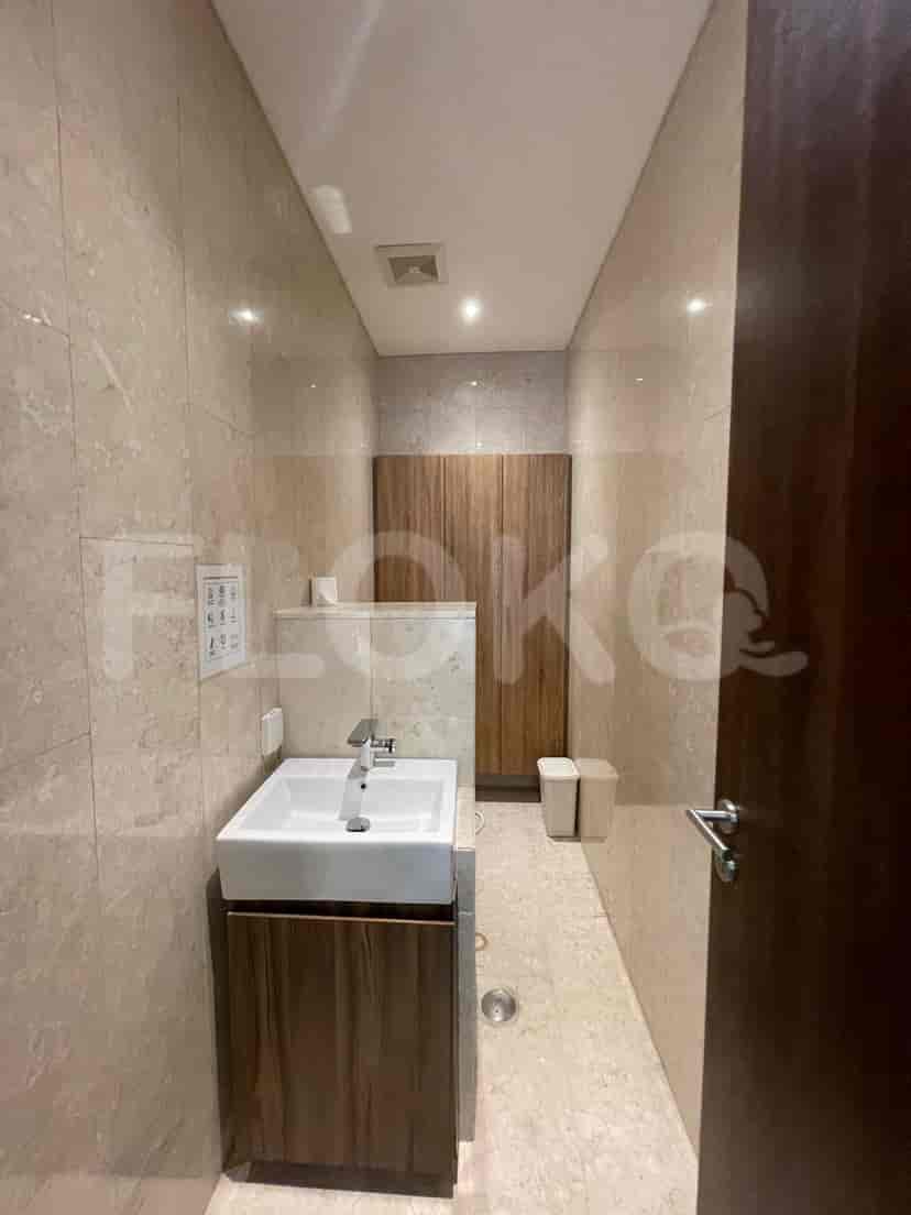 Bathroom with neutral-toned tiles, sink, and wooden storage.