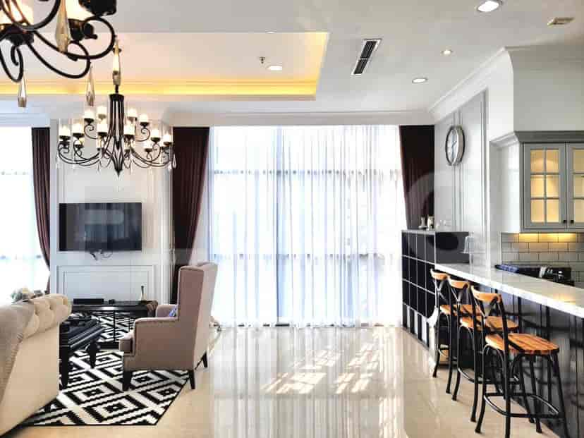 Ruang tamu dan dapur dengan lampu gantung, TV, dan kitchen island.