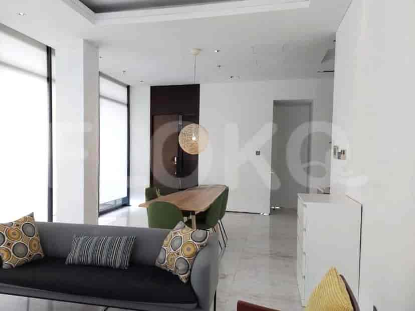 Modern living room with a grey sofa, dining table, and a round pendant light.