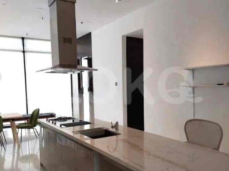 A sleek kitchen with a central island, stainless steel hood, and built-in appliances.