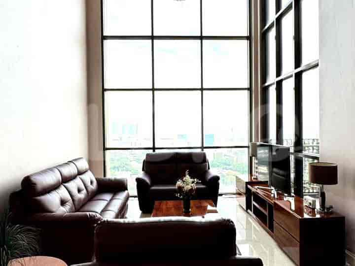 Ruang tamu mewah dengan sofa kulit, jendela besar, dan TV.