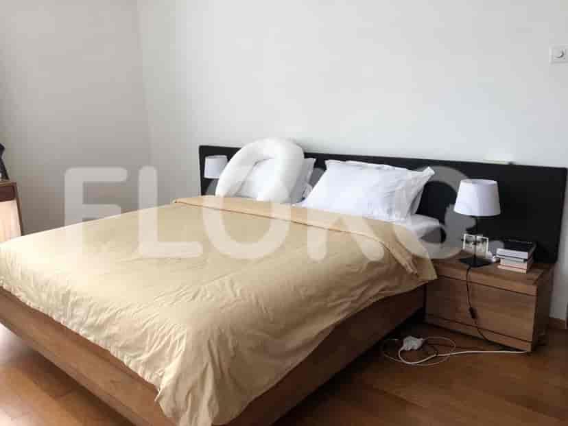 A bedroom with a wooden bed and neutral-toned bedding.