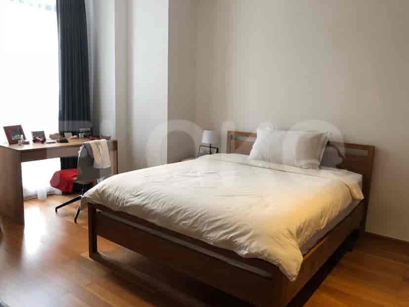 A simple bedroom featuring a wooden bed, desk, and neutral decor.