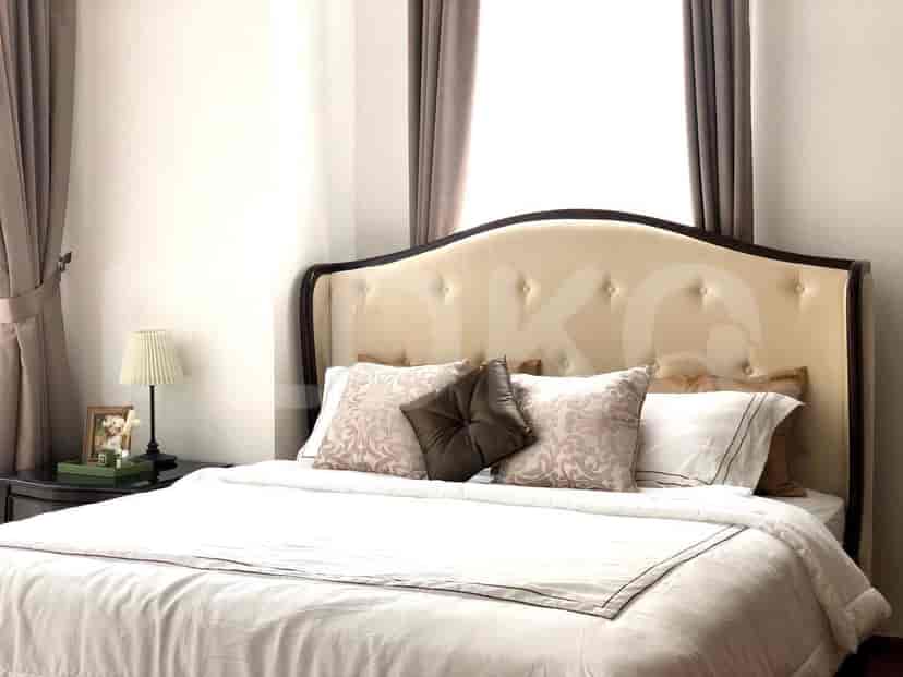 A bedroom featuring a bed with a decorative headboard and side tables.