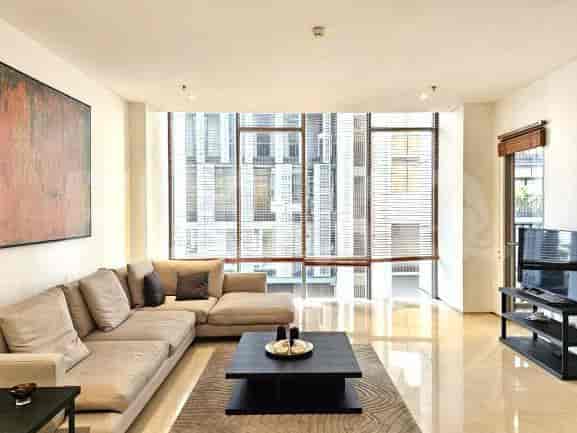 A modern living space with a neutral color palette, featuring a large sectional sofa and a view of city buildings through a window.