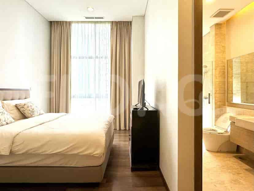 A bedroom featuring a large bed, TV, and a view through the curtains.