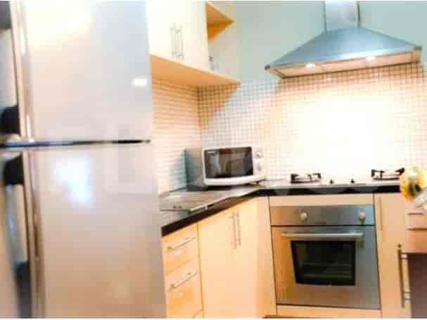 A modern kitchen with wooden cabinets, a stainless steel oven, and a microwave.