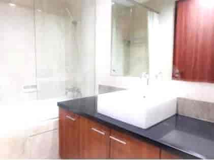 A modern bathroom with a white sink, black countertop, and a shower.