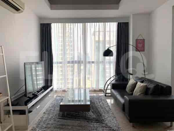 Living room featuring a TV, dark sofa, and large windows with curtains.