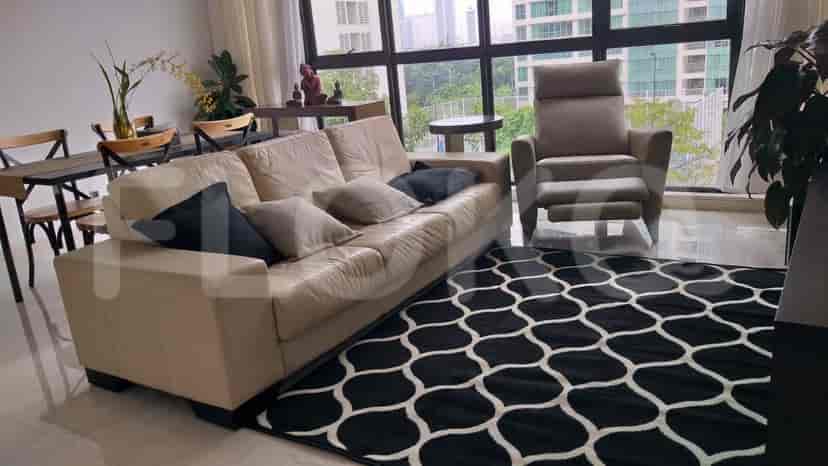A bright living room with a beige sofa, patterned rug, and large windows.