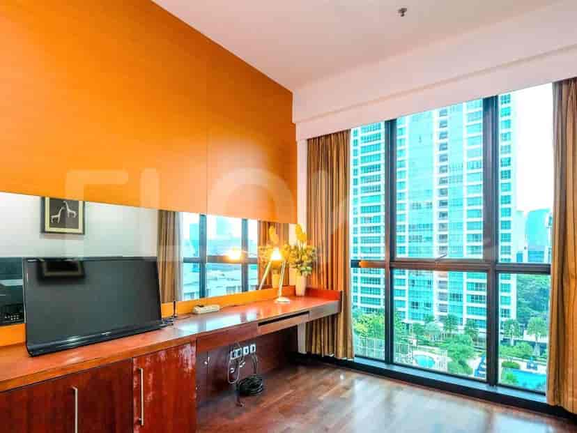 Bedroom with a desk area, a TV, and a view of the city through the windows.