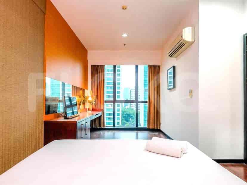 Bedroom with a dressing table and large windows overlooking the city.