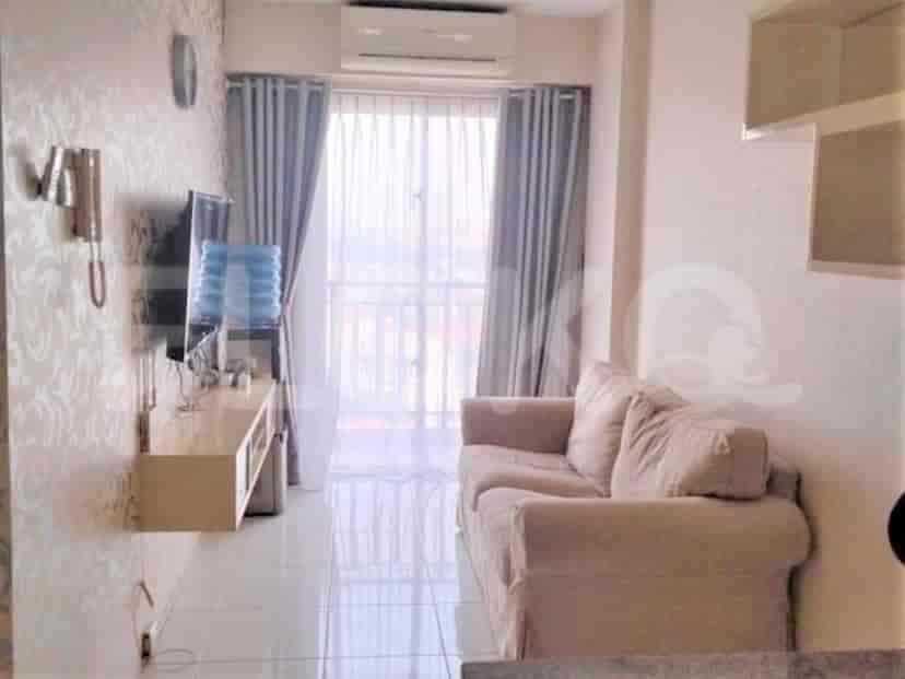 A cozy living room with a sofa, TV, and large window.