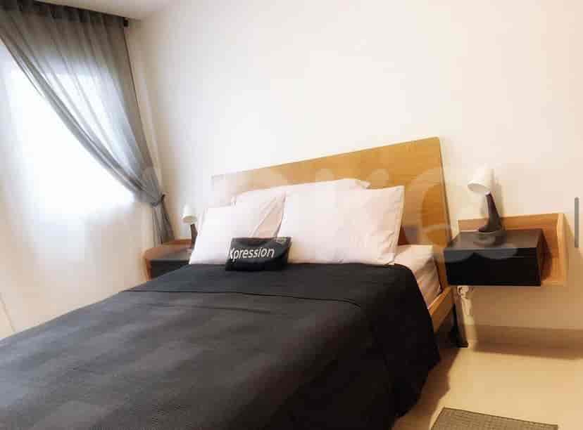 A bedroom with a wooden bed frame, black bedding, and nightstands with lamps.