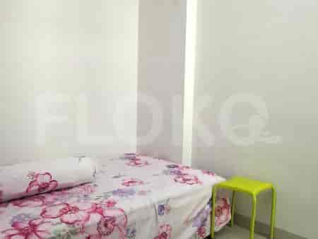 A cozy bedroom with a bed, a small green stool, and a floral bedspread.
