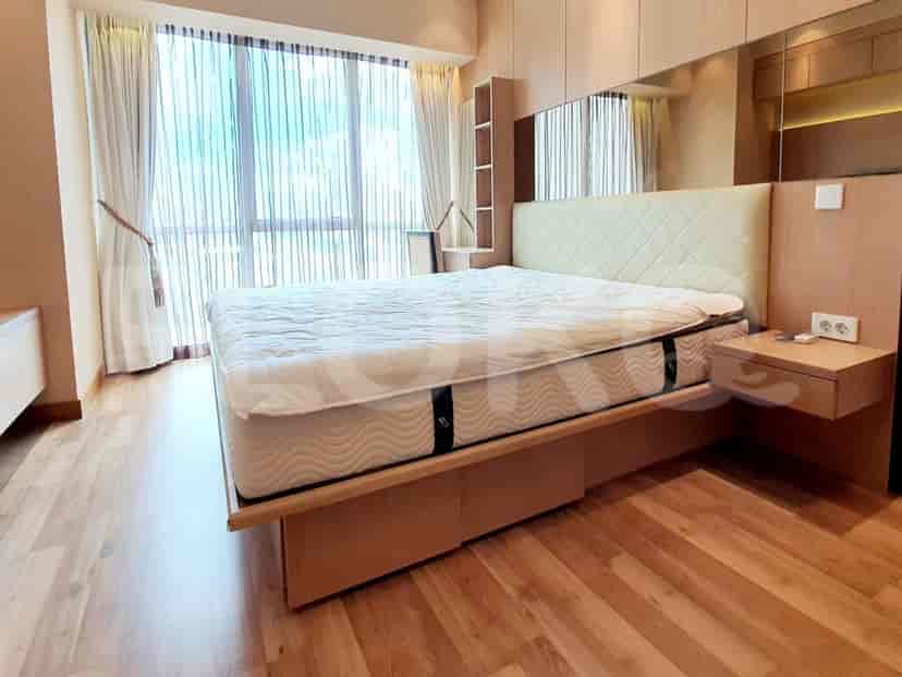 A modern bedroom with a large bed, wooden flooring, and a window with curtains.