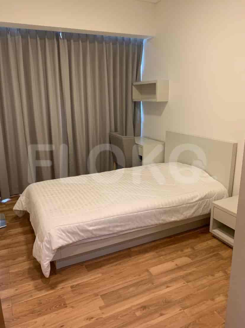 A bedroom with a bed, a desk, and a nightstand.