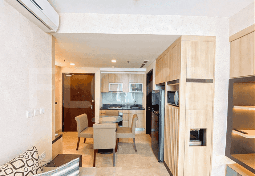 A combined kitchen and dining area with wooden cabinets and a round glass table.