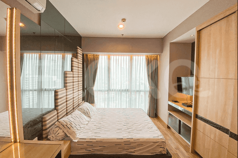 A master bedroom with a large bed, wardrobe, and window with curtains.