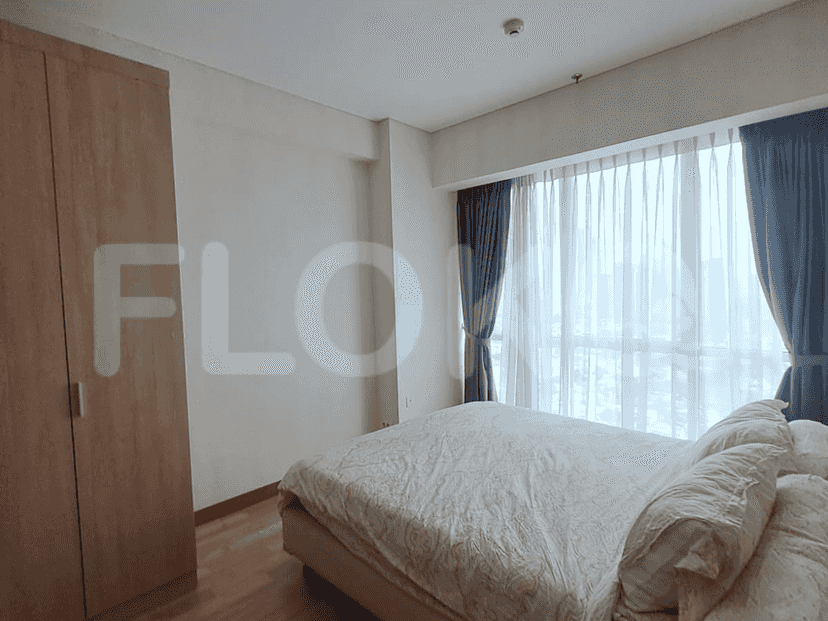 Bedroom with a large bed, wardrobe, and a window with sheer curtains.