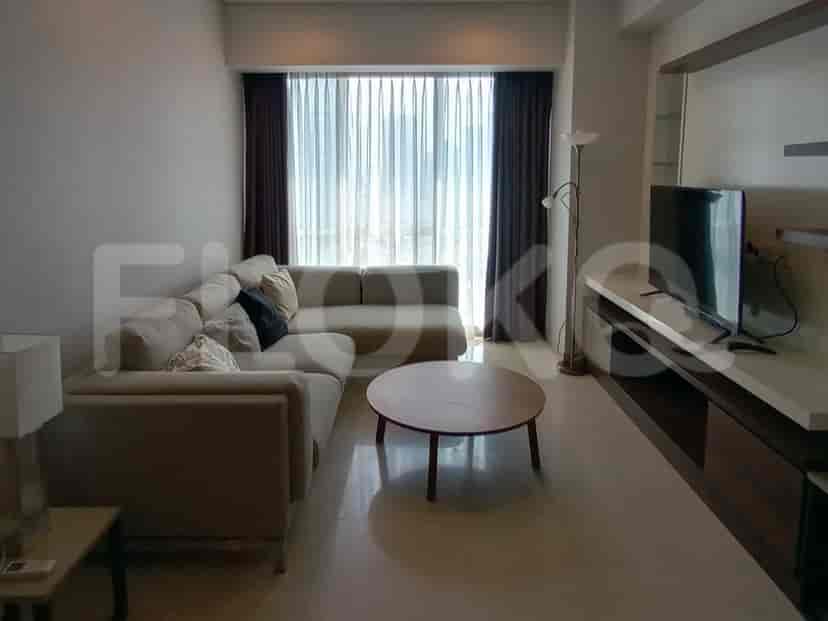 Spacious living room with an L-shaped sofa, smart TV, and large windows with sheer curtains.