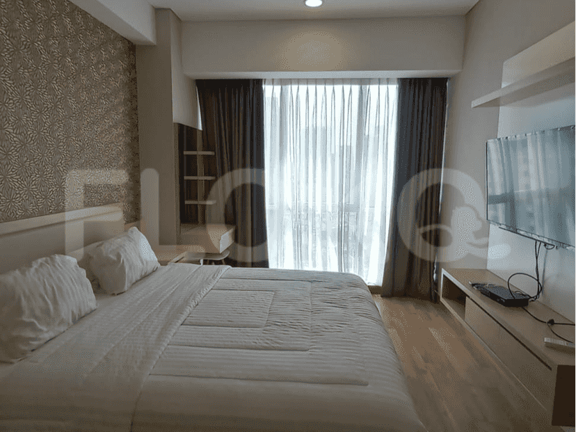 Bedroom featuring a large bed, TV, and a window with curtains.