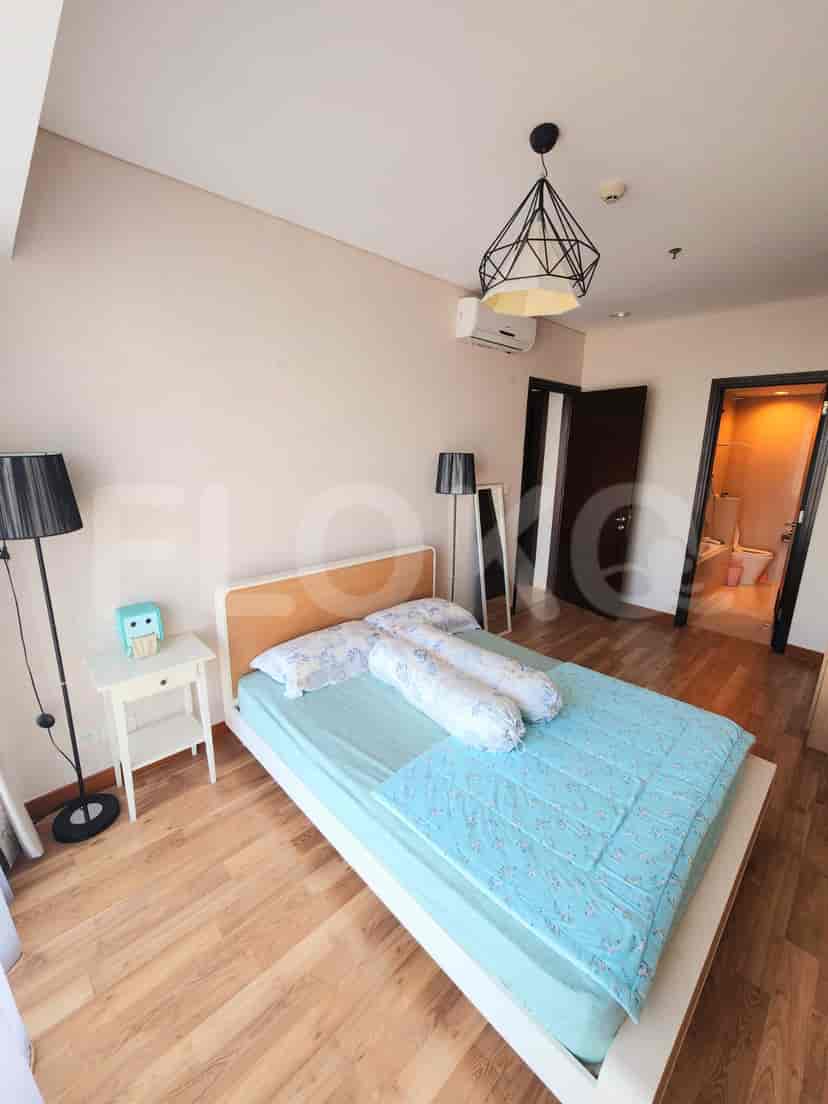 A bedroom with a double bed, side table, and floor lamp.