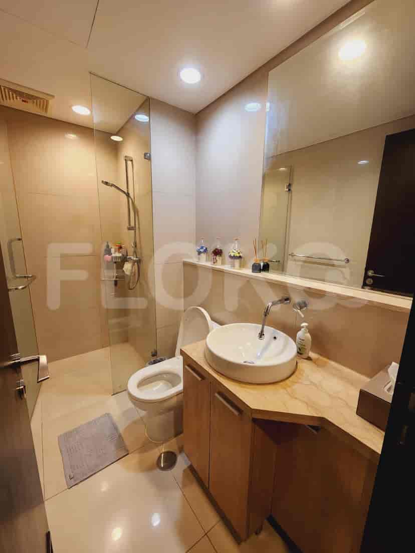 A modern bathroom featuring a glass shower enclosure, vanity with a round sink, and neutral-toned tiles.