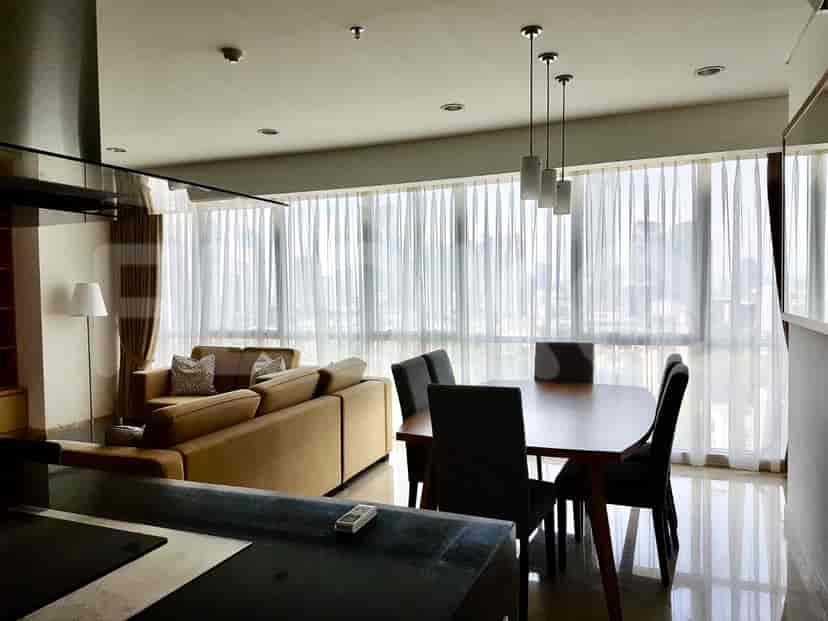 A dining area adjacent to the living room, featuring a wooden dining table and chairs, with large windows.