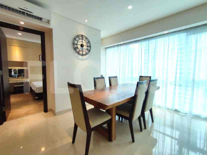 A dining room with a wooden table and chairs with a view of a bedroom.