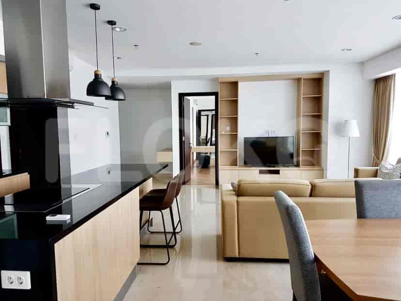 Spacious living area with a sofa, dining table, TV, and kitchen access.