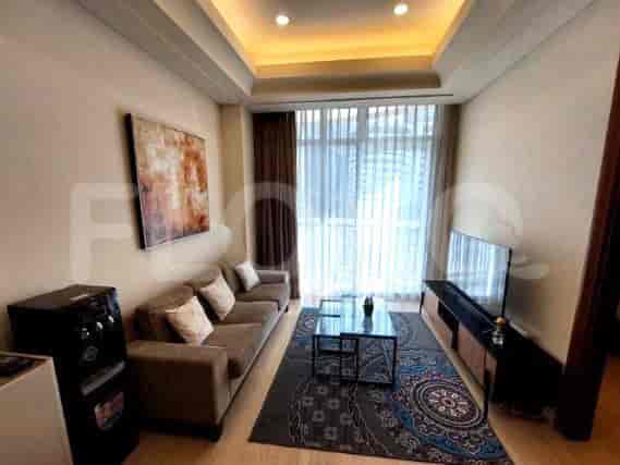 A modern living room with a grey sofa, wall-mounted TV, and large windows with sheer curtains.